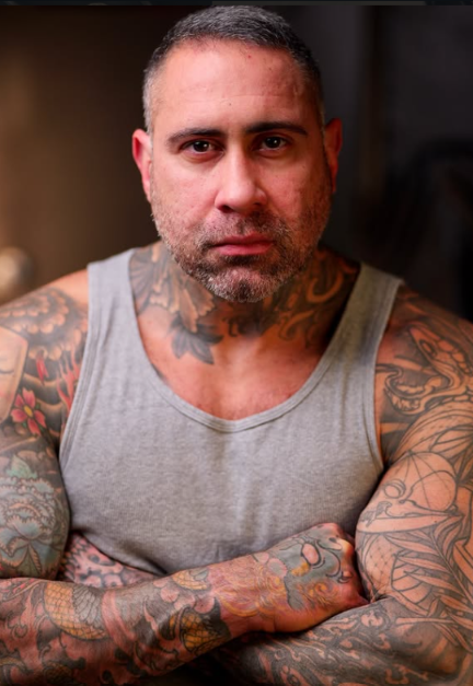 Diego Waller, seated with arms crossed, wearing a gray training tank
