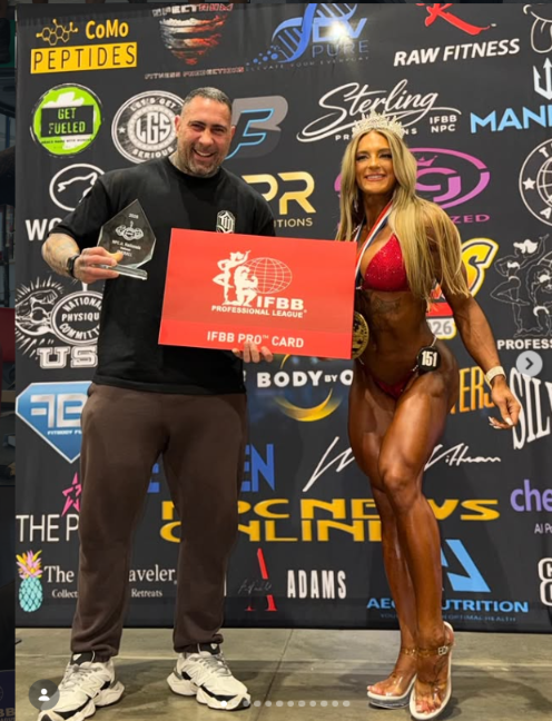 Diego alongside a competition athlete holding an IFBB Pro Card presentation sign
